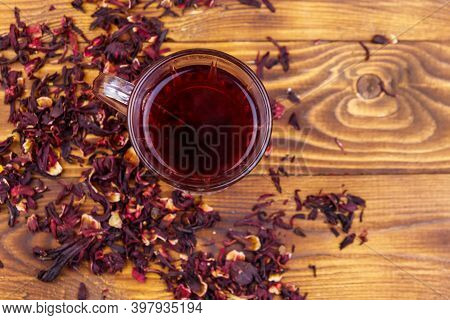 Glass Cup Of Red Hibiscus Tea (carcade, Roselle) On Wooden Table