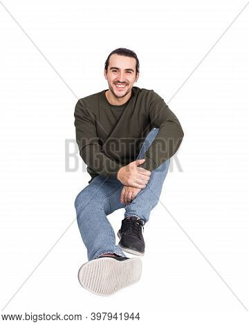 Contented Casual Young Man Sitting On The Floor Smiling To Camera. Lifestyle Full Length Portrait Ha