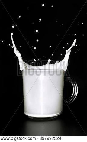 Milk Splash In A Glass Mug On Black Background