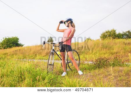 Portrait Of A Young Female Sport Athlete With Racing Bike Resting Outsie.