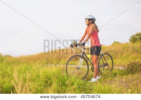 Portrait Of A Young Female Sport Athlete With Racing Bike Resting Outsie.