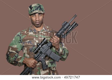 Portrait of African American US Marine Corps soldier holding M4 assault rifle over brown background