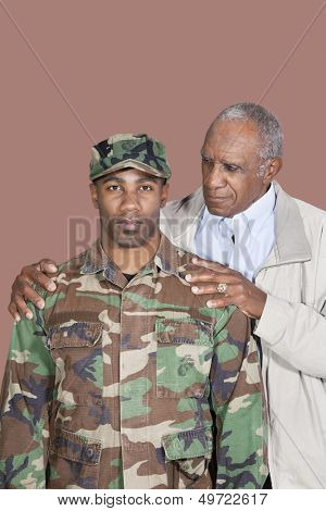 Portrait of African American male US Marine Corps soldier with father over brown background