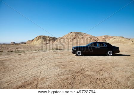Luxury car parked on unpaved road near mountains