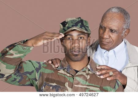 Portrait of US Marine Corps soldier with father saluting over brown background