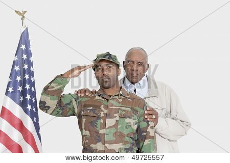 Portrait of father with US Marine Corps soldier saluting American flag over gray background