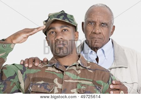 Portrait of US Marine Corps soldier with father saluting over gray background