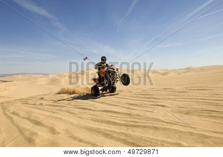 Young quad bike rider doing wheelie in desert
