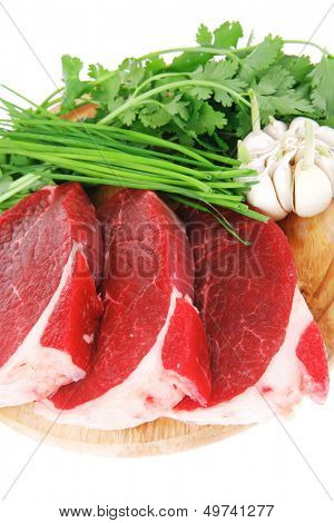 fresh meat : raw uncooked fat lamb pork fillet with green stuff and garlic on wooden plate isolated over white background