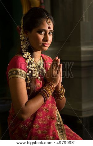 Young Indian female in traditional sari dress praying in a hindu temple.