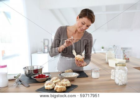 Woman in kitchen preparing cream puffs
