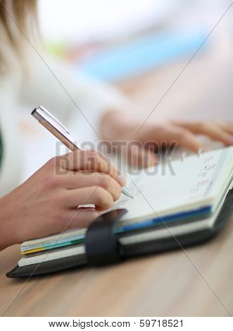 Closeup of woman's hand writing on agenda