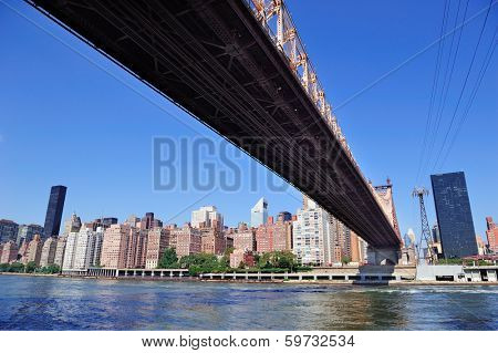 Queensborough Bridge in Midtown Manhattan with New York City skyline over East River as the famous landmarks viewed from Brooklyn.