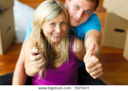 Woman And Man Holding A Key With Thumbs Up. Buying New House
