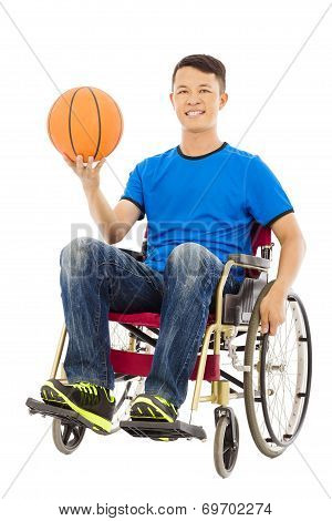 Hopeful Young Man Sitting On A Wheelchair With A Basketball