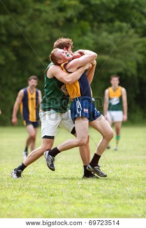 Player Grimaces While Being Tackled In Australian Rules Football Game