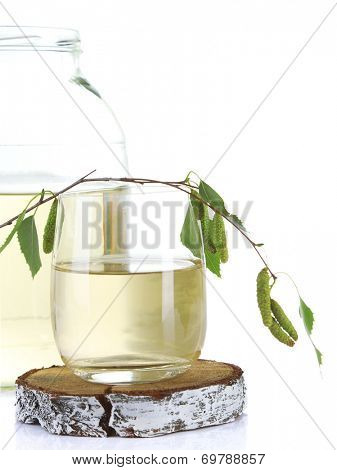 Glass and large flagon of fresh birch sap isolated on white