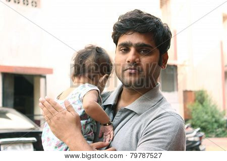 Indian father smiling and holding his baby