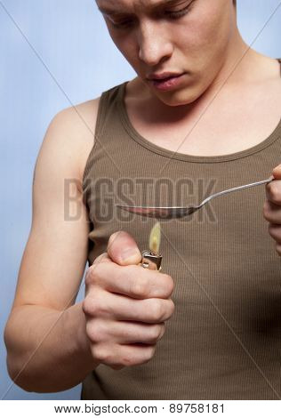 Man with a hardline drug addiction heating drugs in a spoon over a flame 