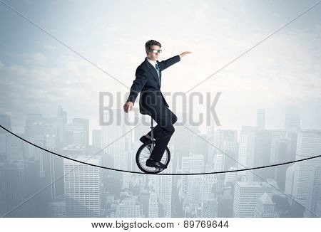 Brave guy riding a monocycle on a rope above cityscape concept