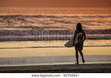 Surfer On The Beach At Sunset Tme