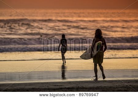 Surfer On The Beach At Sunset Tme