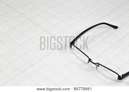 Eyeglasses Put On White Patchwork Quilt Background