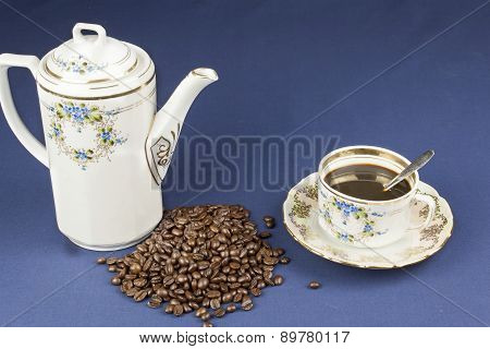 coffee mug on the table with a blue tablecloth, poured out coffee beans