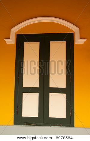 Weißes Fenster mit grünen Rahmen auf gelbe Wand.