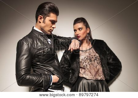 Beautiful young fashion woman leaning on a wall while her lover is lening on her.