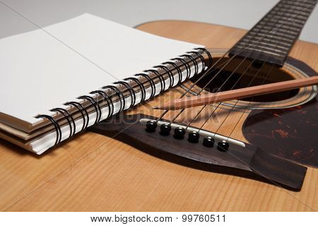 A Notebook and pencil on a guitar