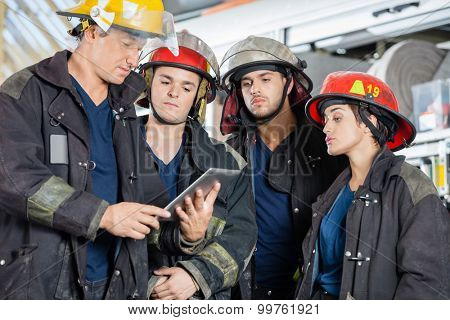 Team of firefighters using tablet computer at fire station