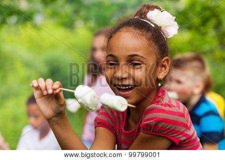 Happy African girl holding stick with marshmallow