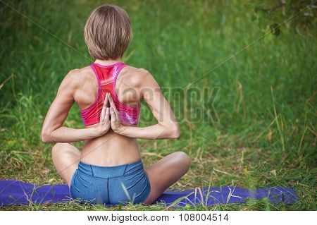Young Caucasian woman sitting with hands folded behind her back