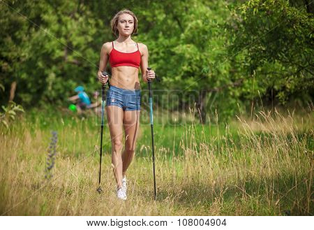 Fit young woman hiking with nordic walking poles.