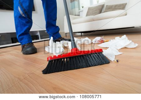 Janitor Sweeping Crumpled Papers On Floor