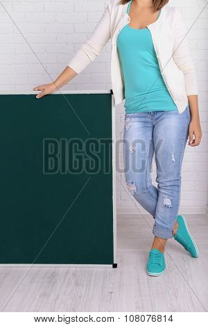 Woman in causal with green blackboard against brick wall, close up
