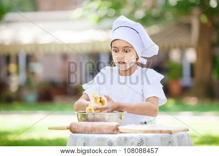 Astonished little chef holding ducklings while cooking