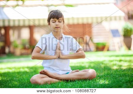 Little girl meditating while sitting in lotus position