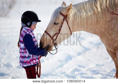 Little girl with horse outdoor in winter