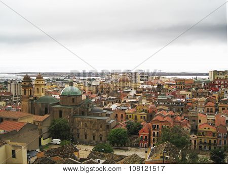 Cagliari's Skyline With Buildings, Port, Sea And Gloomy Grey Cloudy Sky