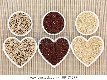 Quinoa health and super food varieties in heart and round shaped porcelain bowls over bamboo background.