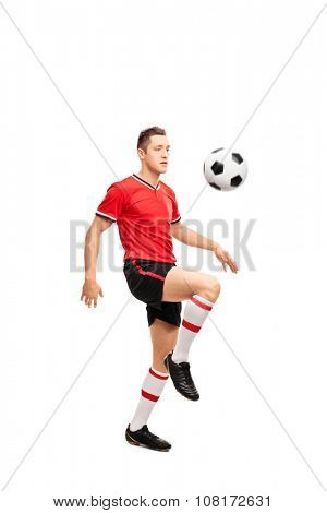 Full length portrait of a young football player juggling a ball on his knees isolated on white background