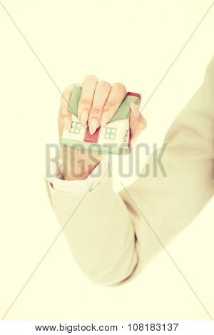 Aggresive businesswoman crushing small house.
