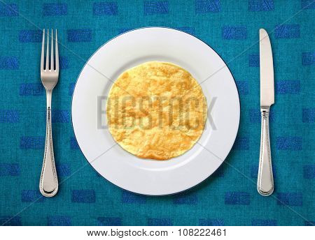round white plate with slapjack, knife and fork on table 