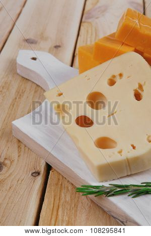 various types of fresh raw aged delicatessen cheese on white plate over light wooden table cheddar edam swiss