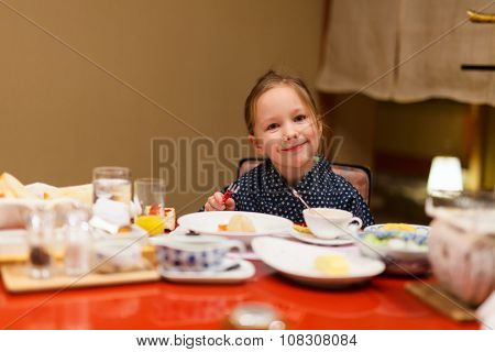 Adorable little girl wearing traditional yukata kimono eating Japanese breakfast
