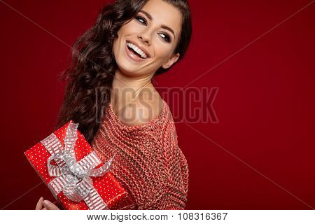 Beautiful woman portrait hold gift in christmas color style . Smiling happy girl on red background.