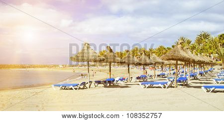 Straw Umbrellas And Loungers On The Playa De Las Americas, Tenerife