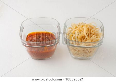 a small portion of linguini pasta and pasta tomato sauce in a glass storage container